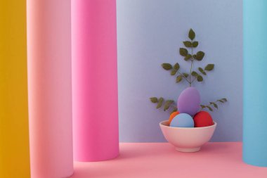 Beyaz kâse üzerinde Paskalya yumurtaları. Renkli arka plan.