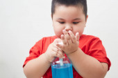 Asia Boy kezében üveg fertőtlenítő tisztító gél. A vírus és a baktériumok megelőzése