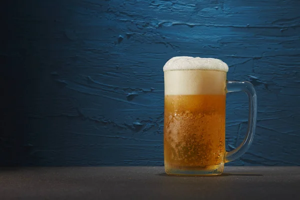 Beer in mug on table with rough blue background