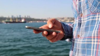 arka plan deniz manzaralı üzerinde cep telefonu kullanan adam yakın eller yukarı