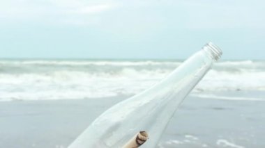 Genç adam açılış mesajı bir şişe kum plaj