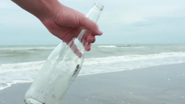 Fiatal férfi záró üzenet a palackban a homokos strand — Stock videók