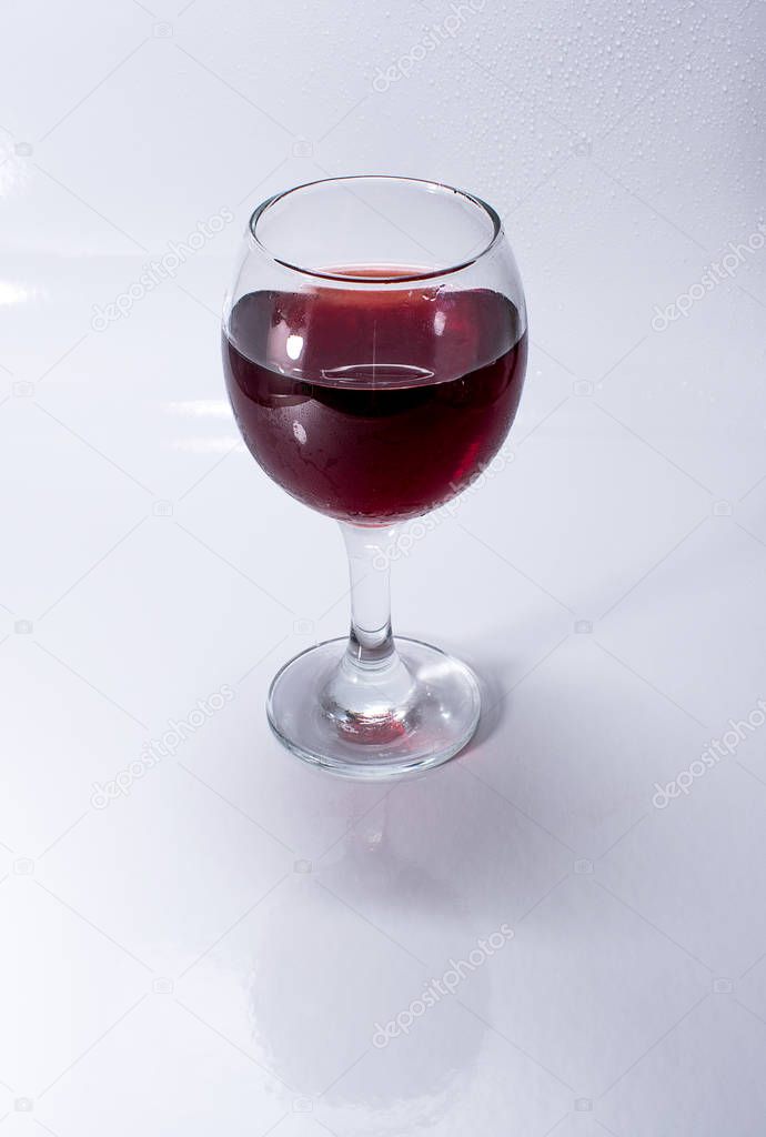 A glass of red wine on a white glossy surface