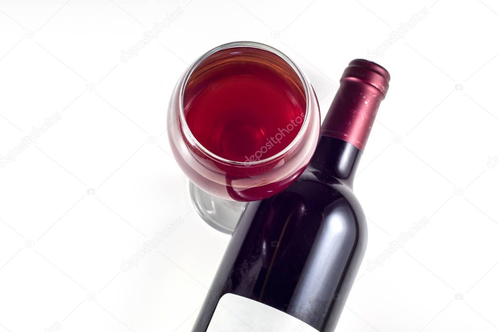 A glass and a bottle of red wine on a white background. View from above.