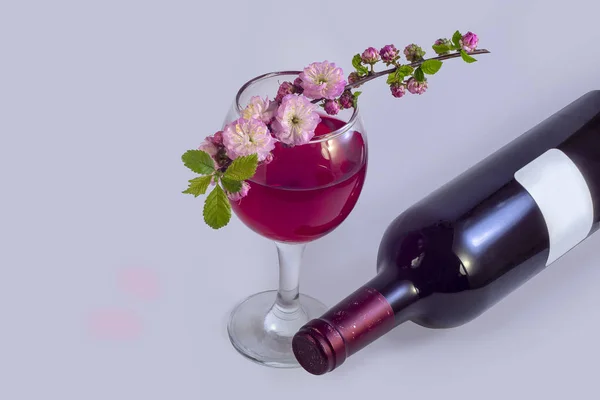 樱花的春天粉红色花洒在一杯红酒旁边 旁边是一瓶葡萄酒 柔和的浅色背景 — 图库照片