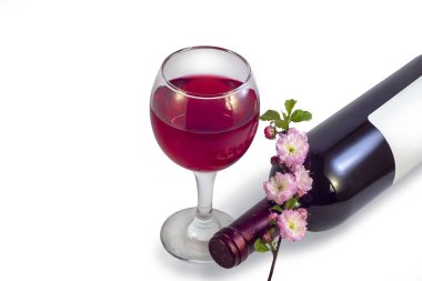 Bir kadeh kırmızı şarap, bir şişe şarap ve beyaz bir arka plan üzerinde pembe çiçek bir parça