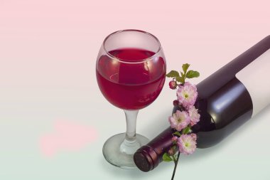 Bir kadeh kırmızı şarap, bir şişe şarap ve pembemsi yeşil pastel arka plan üzerinde pembe çiçek bir sprig