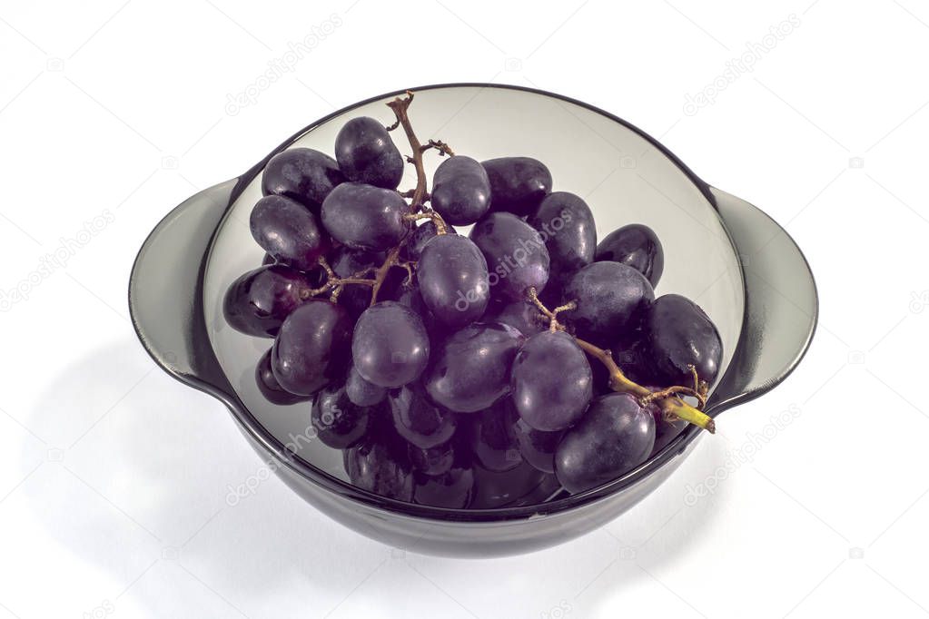 Plate with black ripe grapes on a white background