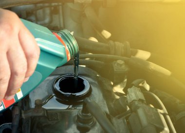 Adam arabanın kaputu altında kaba motor yağı dökülen