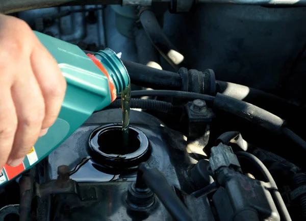 Adam arabanın kaputu altında kaba motor yağı dökülen