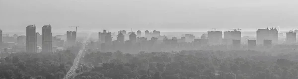 Smog over the horizon of the city. The city is in a fog, black and white. The photo is stretched horizontally