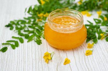 Akasya çiçekli bal, açık ahşap arka planda.