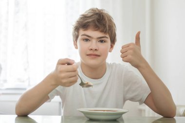 The teenager is having breakfast. He likes breakfast. clipart
