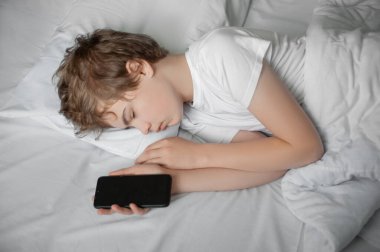 Ergen, elinde telefonuyla yatakta uyuyakaldı..