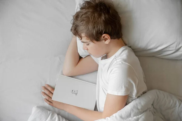 O adolescente dorme na cama. Adormeceu com o livro. . — Fotografia de Stock