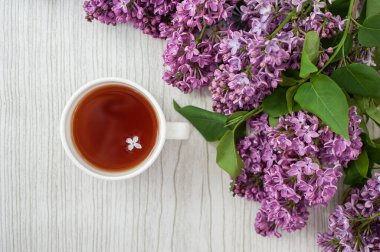 Leylak çiçekli bir fincan çay. Yapraklı leylak. Kırsal tarzda gri ahşap arkaplan.