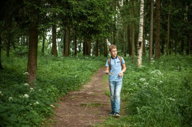 Genç bir harita ve bir pusula ile seyahat ediyor. Çocuk ormanda yürüyor..