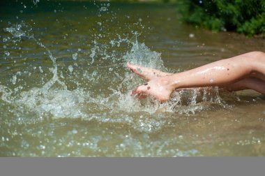 Nehir ya da göl kıyısında. Bir yaz gününde ayaklarım su sıçratıyor..