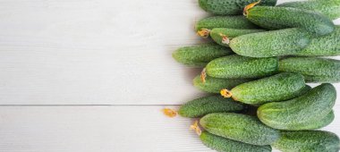 Beyaz ahşap arka planda küçük salatalıklar.