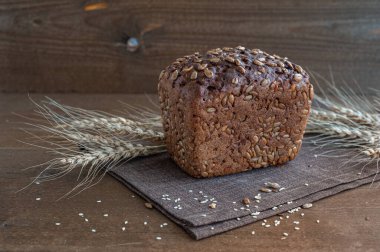 Kahverengi ahşap arka planda ayçiçeği tohumlu bir somun tam tahıllı ekmek..