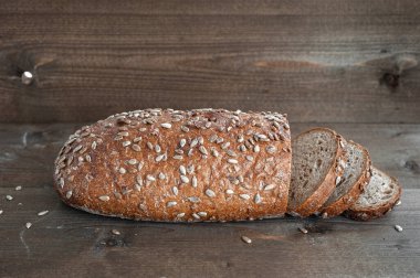 Bir somun taze kepekli ekmek Ahşap bir arka planda parçalara bölünmüş.