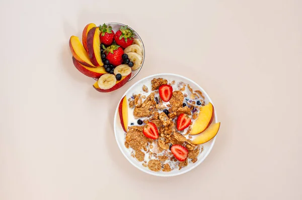 Nyári reggeli. Granola és búzapehely gyümölcsökkel, bogyókkal és tejjel, világos rózsaszín háttérrel. Kilátás felülről. — Stock Fotó