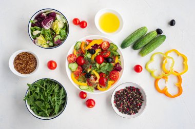 Renkli sebzelerden oluşan vejetaryen salatası ve içeriği beyaz beton bir zemin üzerine kuruludur.