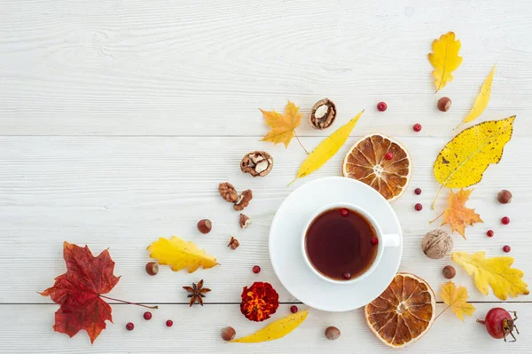 Beyaz ahşap arka planda çay ve kurutulmuş portakallarla sonbahar düzeni.
