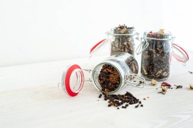 Beyaz ahşap arka planda farklı çay çeşitleri olan kavanozlar. Seçici odaklanma. Metin için bir yer.