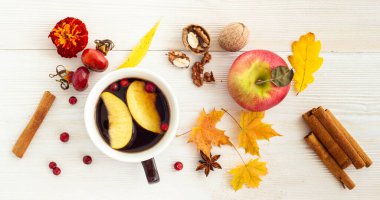 Sonbahar çayı. Beyaz ahşap arka planda düşmüş yapraklı, elmalı ve fındıklı bir fincan çay.. 