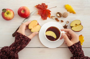 Sonbahar çayı. Bir fincan çay ve elmayla kadın eli. Yukarıdan görüntüle.