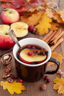 Elma ve böğürtlenli sonbahar çayı. Bir fincan çay, düşen yapraklar ve elmalarla dolu ahşap bir masa. Sonbahar pikniği. 