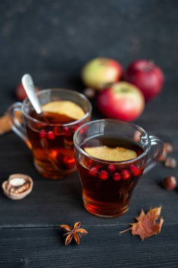 İki bardak sonbahar çayı, böğürtlenli ve elmalı, siyah ahşap arka planda. Sıcak çilek çayı.