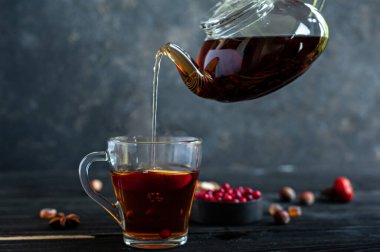 Sıcak siyah çay, bir çaydanlıktan koyu arka plandaki bir fincana dökülür..