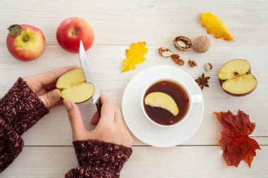 Sonbahar çayı. Elmaları beyaz tahta bir masada dilimleyen eller.. 