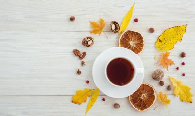 Beyaz ahşap arka planda çay ve kurutulmuş portakallarla sonbahar düzeni.