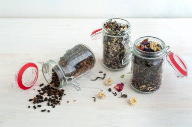 Beyaz ahşap arka planda farklı çay çeşitleri olan kavanozlar. Seçici odak.