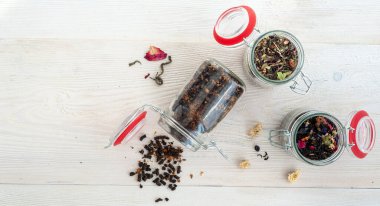 Beyaz ahşap arka planda farklı çay çeşitleri olan kavanozlar. Metin için bir yer.