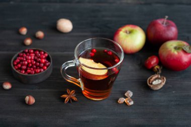 Koyu ahşap arka planda bir fincan sıcak çay. Meyveli, tarçınlı ve elmalı sıcak içecek. Fındıklı sonbahar atıştırması.