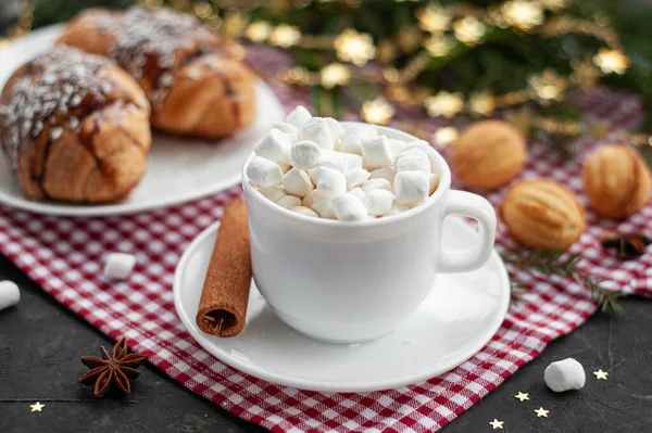Christmas breakfast. Christmas morning. A cup of coffee or cocoa with marshmallows and cinnamon and croissants on a dark table with lights. Selective focus. The atmosphere of Christmas. — Stock Photo, Image