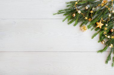 Yılbaşı planı. Beyaz ahşap arka planda ladin dalları, sarı toplar ve diğer altın Noel süslemeleri. Metin için bir yer