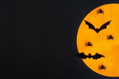 Halloween. Composition. Black bats and spiders against the orange moon and black background. Copy space. clipart