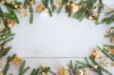 Yılbaşı planı. Beyaz ahşap arka planda ladin dalları, sarı toplar ve diğer altın Noel süslemeleri. Metin için bir yer.