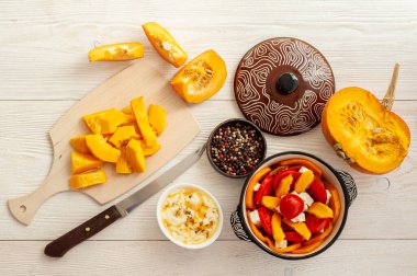 Beyaz ahşap arka planda balkabağı güveci pişirme işlemi.