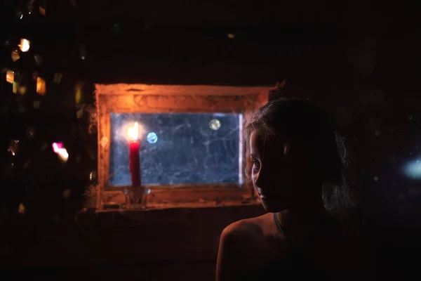 薄明かりの中で木造住宅の窓辺の少女 — ストック写真