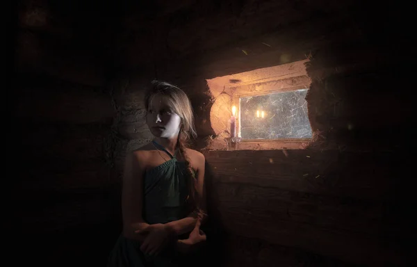 girl by the window in a wooden house with dim light