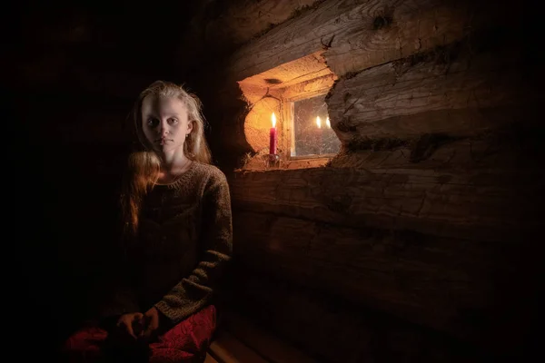 girl by the window in a wooden house with dim light