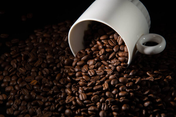 white cups with a pattern and grains of coffee on a black background