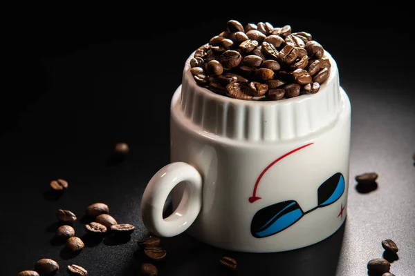 white cups with a pattern and grains of coffee on a black background