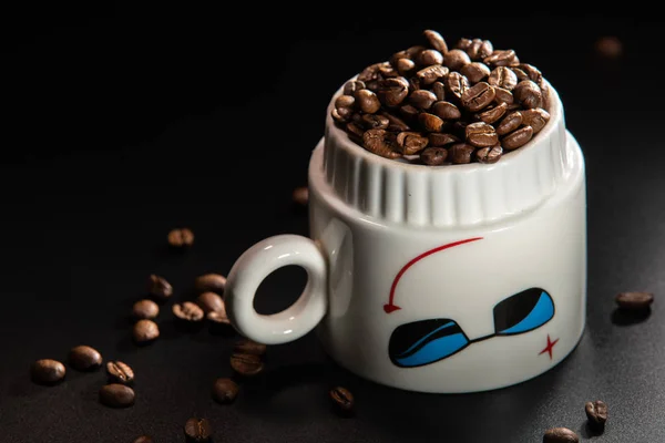 white cups with a pattern and grains of coffee on a black background